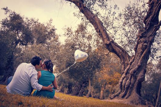 Happy young man piggybacking his girlfriend holding a red heart-shaped balloon