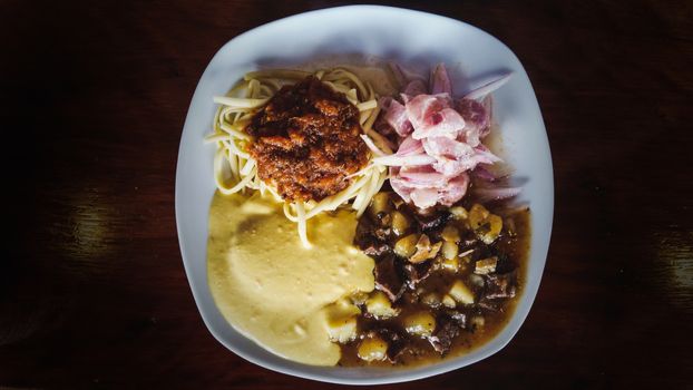 Peruvian cuisine: chanfainita with noodles, ceviche and huancaina sauce served on a flat plate