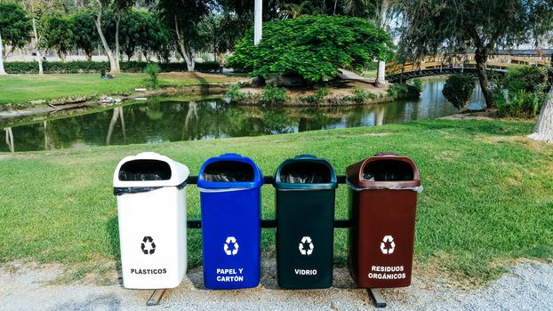 Different Colored Bins For Collection Of Recycle Materials ubicated in a park