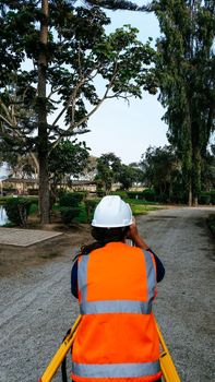 A full-length shot of a rear view of a standing engineer looking through a tool