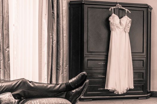 Groom waiting for the bride and the bride's dress hanging