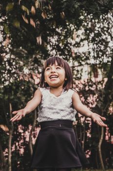 Little cute short-haired girl throws leaves in the park