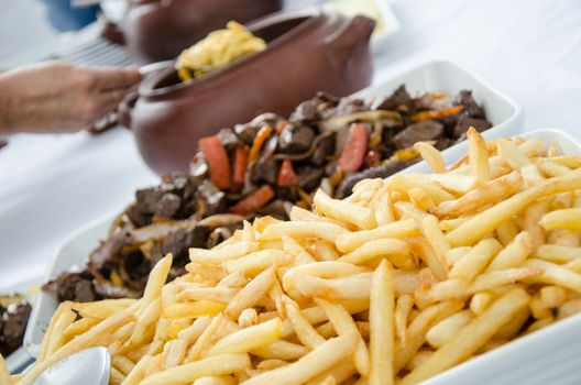 Peruvian dish Lomo saltado - potatoes and in the background defocused the lomo saltado