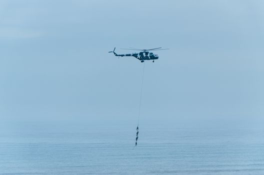 Four men hanging on a rope in a helicopter, doing tests, training