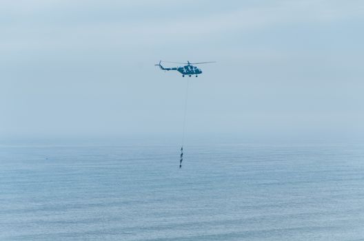 Four men hanging on a rope in a helicopter, doing tests, training