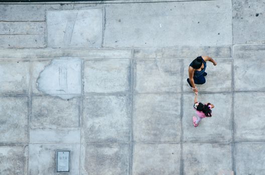 Mother and daughter walking on the pavement. View from above