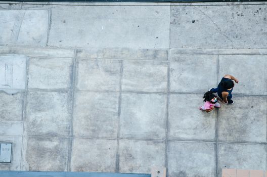 Mother and daughter walking on the pavement. View from above