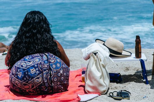Woman resting enjoying summer on the beach, sitting on her back