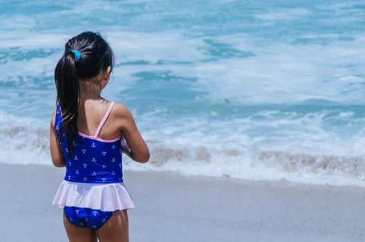 Hands of little girl play with sand on beach