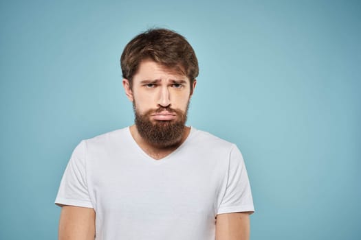 Man in white t-shirt lifestyle studio emotions facial expression blue isolated background. High quality photo