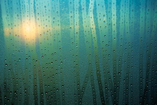 Water droplets on glass with the sunrise in morning.