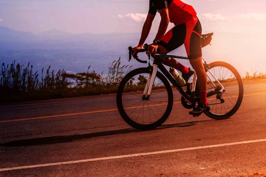 young man was cycling on the road with sun shining in the evening.