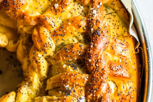 Close up photo with selective focus on details of salt and poppy seeds over a braided puff pastry.