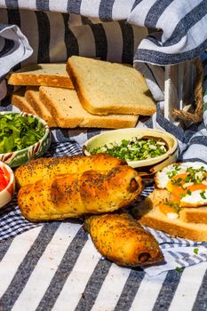 Rustic composition with sausages rolls, fried egg on toast bread, different bowls with sauce and chopped vegetables.