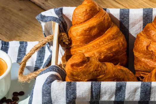 Puff pastry, coffee cup and buttered French croissant on wooden crate. Food and breakfast concept. Detail of coffee desserts and fresh pastries