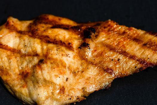 Close up of grilled steak on small black chopping board isolated. Barbecue, grill and food concept.