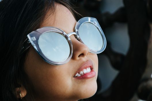 Cute little girl smiling with adult sun glasses
