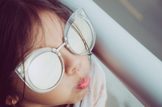 Cute little girl smiling with adult sun glasses