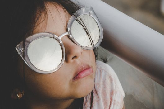 Cute little girl smiling with adult sun glasses