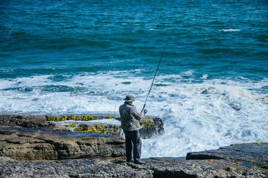 Fisherman on the seashore with his fishing rod