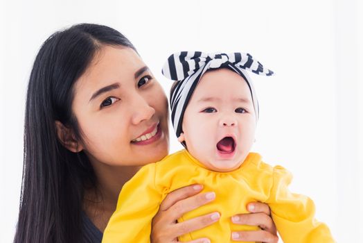 Portrait of beautiful young Asian mother playing and smiling together with his newborn little baby at home, Parent mom and little kid relaxing in the bedroom, Family having fun together