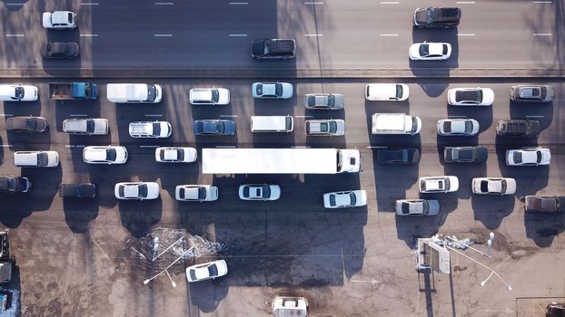 Transport interchange in a big city. Long traffic jam. A huge number of cars pass by. A large trucker's truck is visible. Muddy roads, heavy car exhaust. Bad ecology of the city of Almaty.