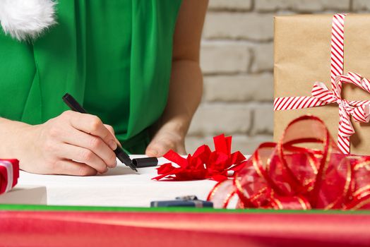 woman signs christmas gifts with a black pen. christmas gifts packing service concept