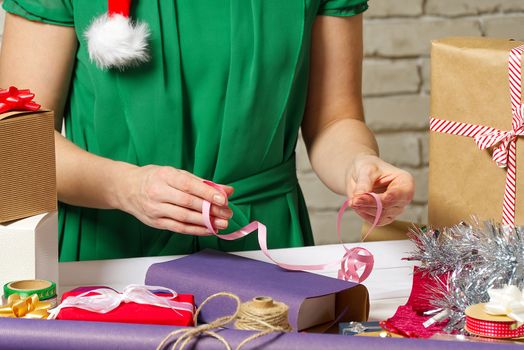 Gift wrapping for Christmas and New Year. Handmade. woman hands with gift ribbon, twine, tape and present wrapped