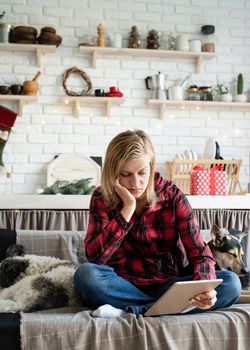 Young depressed woman in working on tablet sitting on the couch