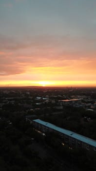 Red sunset over the city of Almaty. Clouds shimmer with different colors from yellow-red to blue. The city is plunged into darkness. Night falls. Lights are on, cars are driving. The view from the top