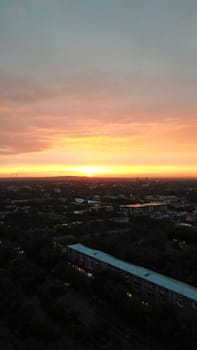 Red sunset over the city of Almaty. Clouds shimmer with different colors from yellow-red to blue. The city is plunged into darkness. Night falls. Lights are on, cars are driving. The view from the top