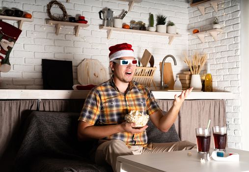 Movie night. Young man in 3D glasses watching movies at home at night at christmas