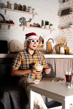 Movie night. Young man in 3D glasses watching movies at home at night at christmas