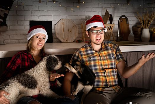 Movie night. Young couple watching movies at home at christmas pointing to the screen eating popcorn