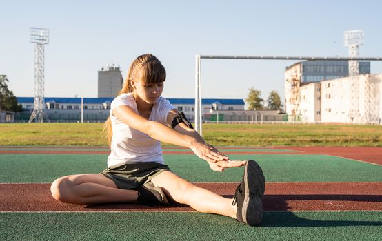 Fitness and sports. Teenager girl doing stretching at the stadium