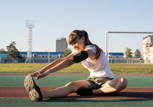 Fitness and sports. Teenager girl doing stretching at the stadium