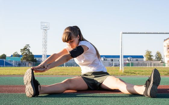 Fitness and sports. Young woman doing stretching at the stadium