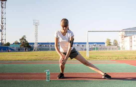 Fitness and sports. Teenager girl doing stretching at the stadium