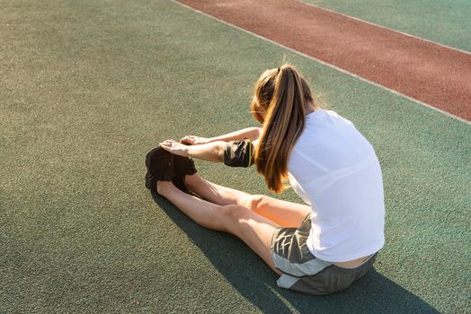 Fitness and sports. Teenager girl doing stretching at the stadium