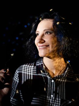 Light and shadow portrait. Beautiful young woman with a shadow pattern oof soap bubbles on her face on black background