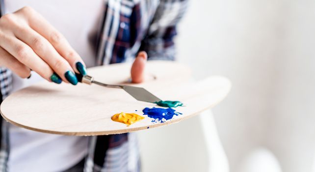 Artist palette. Artist hands mixing paints on the palette. Oil or acryllic painting. Selective focus