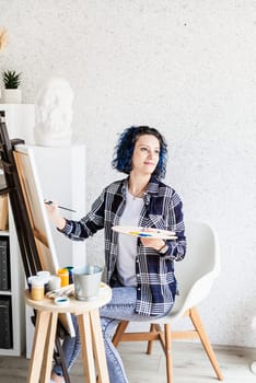 Creative woman artist painting a picture working in her studio