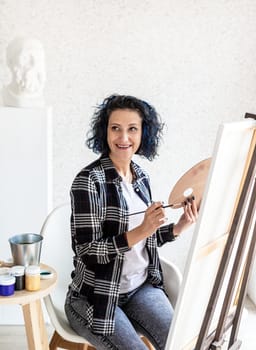 Creative woman artist painting a picture working in her studio