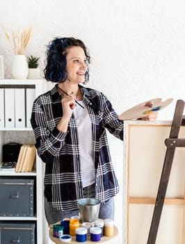 Creative woman artist painting a picture working in her studio