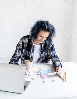 Designer working with colour palettes and laptop in her art studio