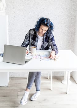 Designer working with colour palettes and laptop in her art studio