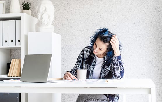 Designer working with colour palettes and laptop in her art studio