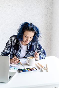 Designer working with colour palettes and laptop in her art studio