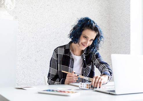 Designer working with colour palettes and laptop in her art studio