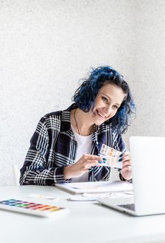 Designer working with colour palettes and laptop in her art studio